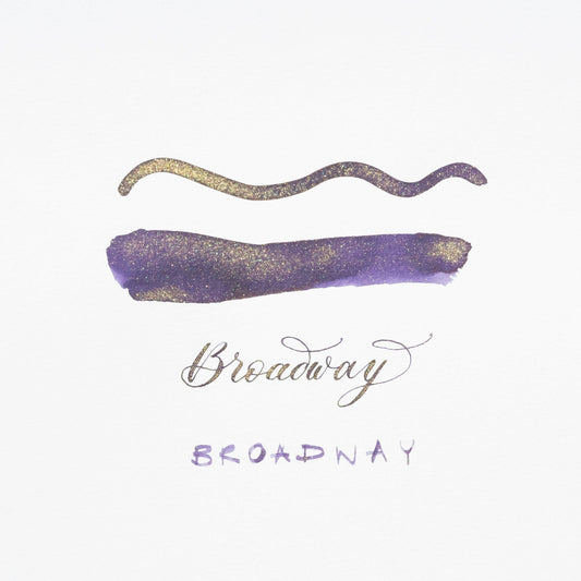 Purple shimmer ink swatch with gold wavy stroke and handwritten label, on white card
