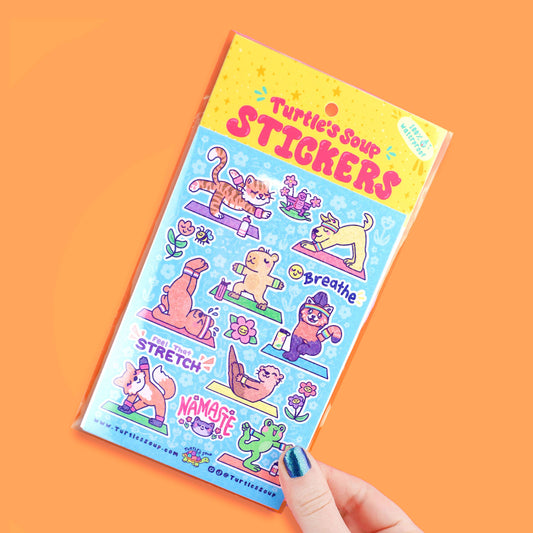 Yoga sticker sheet with cute animal poses, held in hand