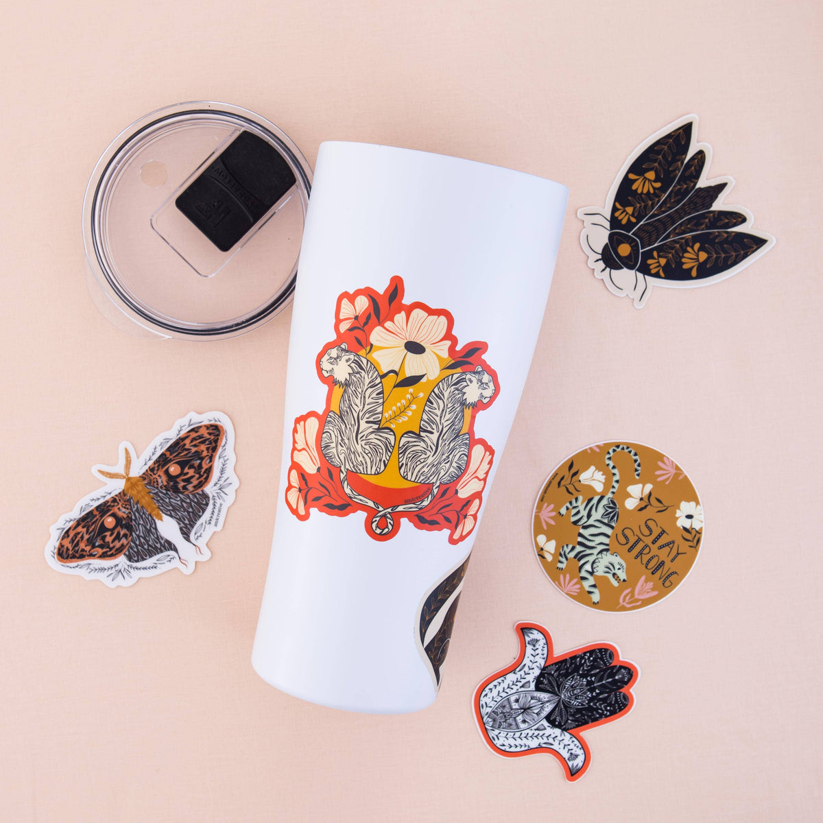 Golden moth clear vinyl sticker with patterned black and rust-colored wings, shown among other stickers