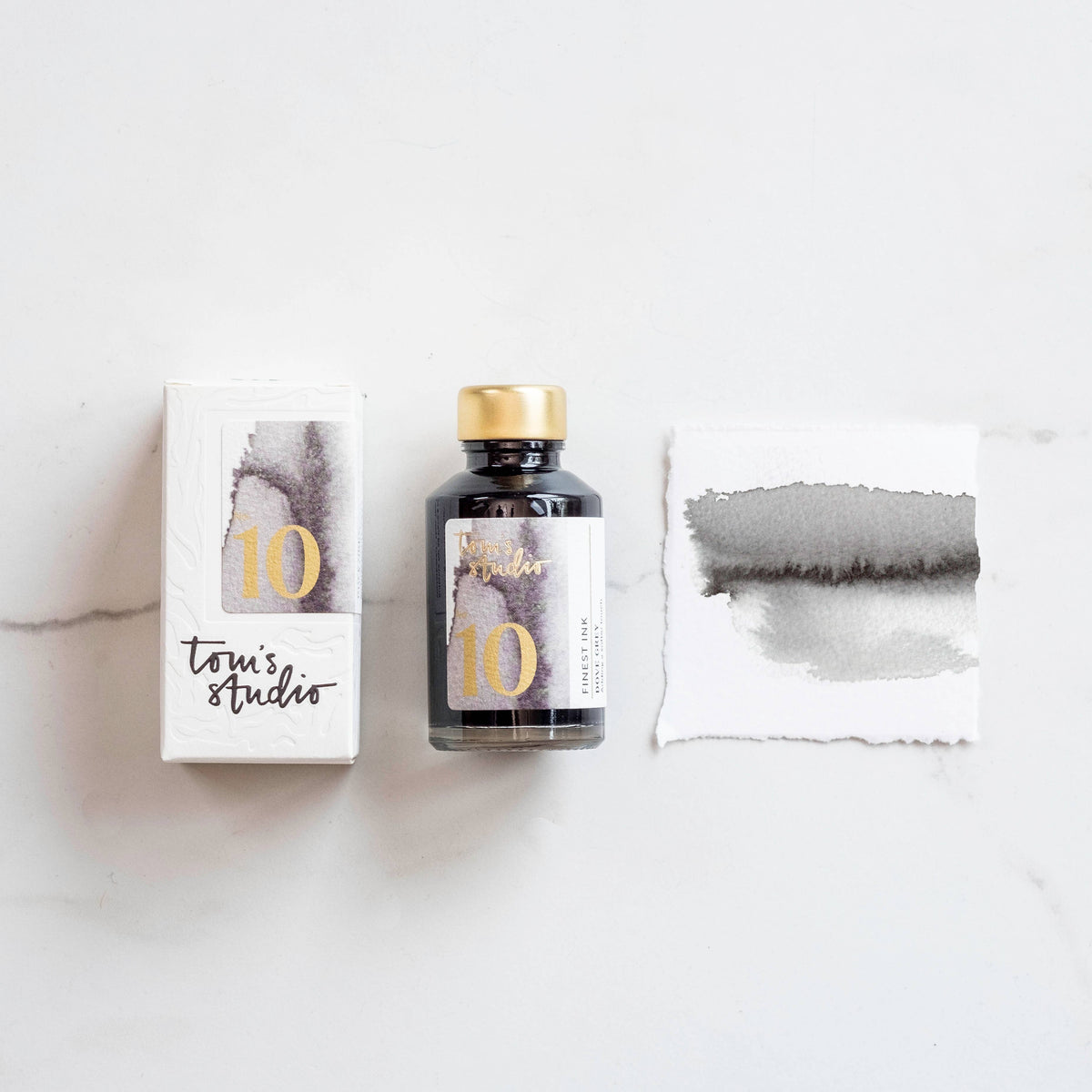 Dove grey fountain pen ink bottle with gold cap and paper swatch