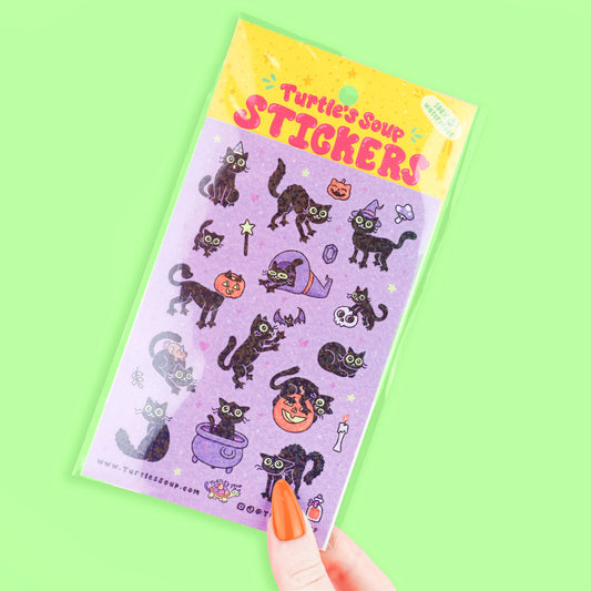 Halloween sticker sheet with black cats and jack-o'-lanterns; hand holding sheet