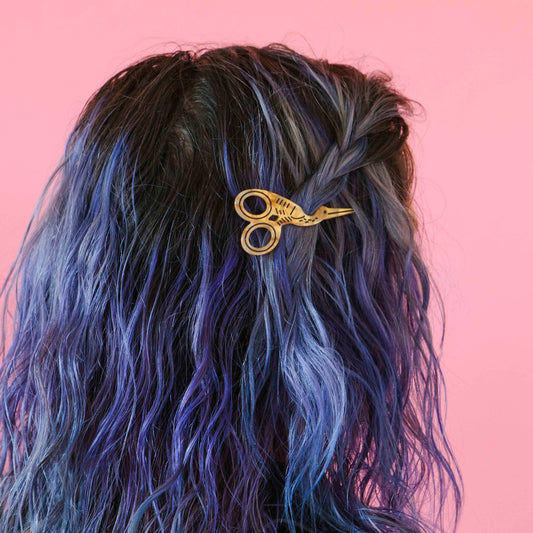 Scissors-shaped hair clip in gold on dark blue hair section