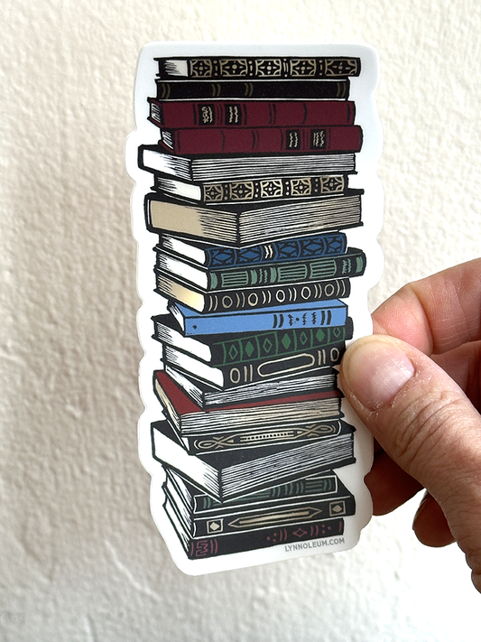 Hand holding book stack sticker with colorful illustrated books on a white die-cut shape