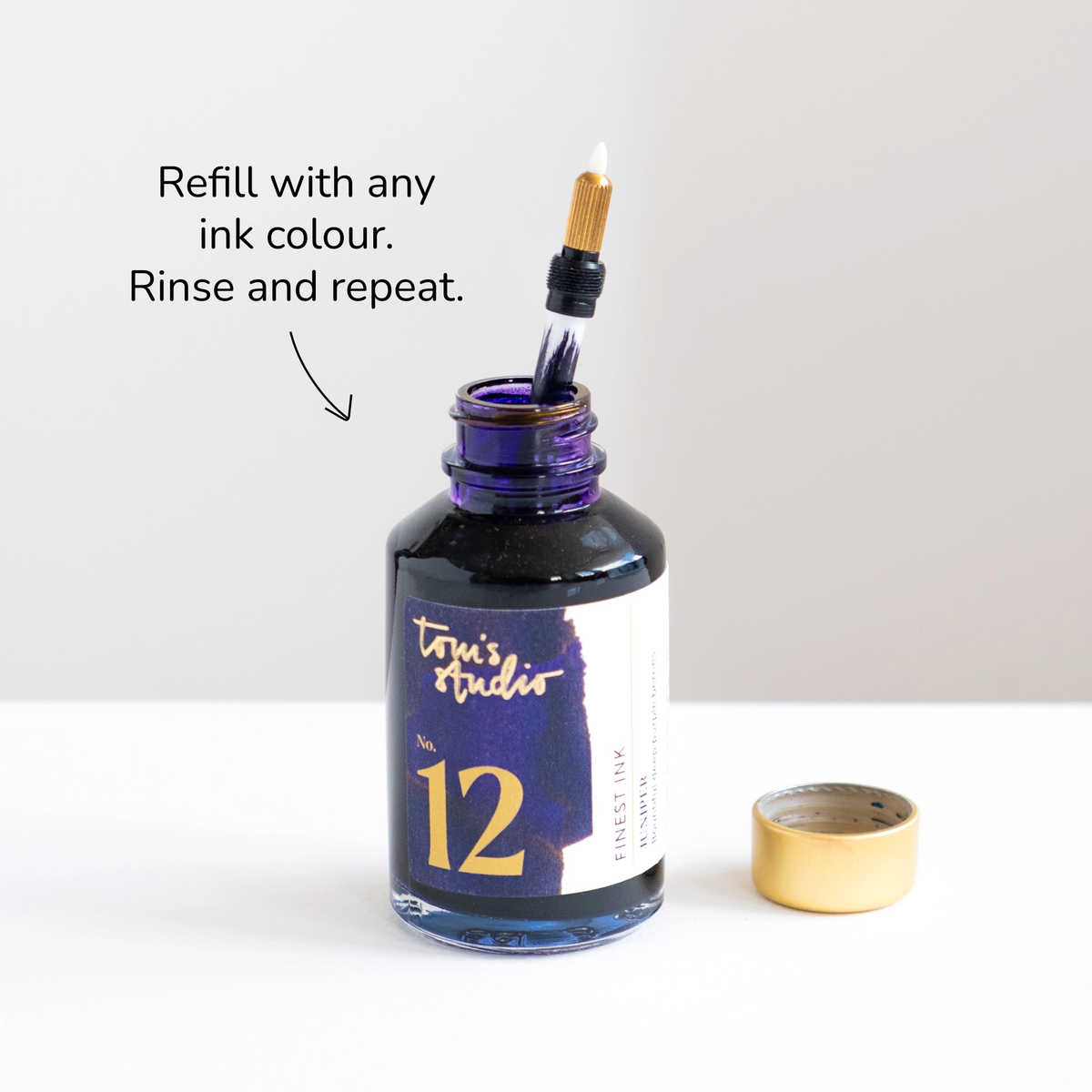 Refill ink bottle with a pen nib inserted and the cap beside it