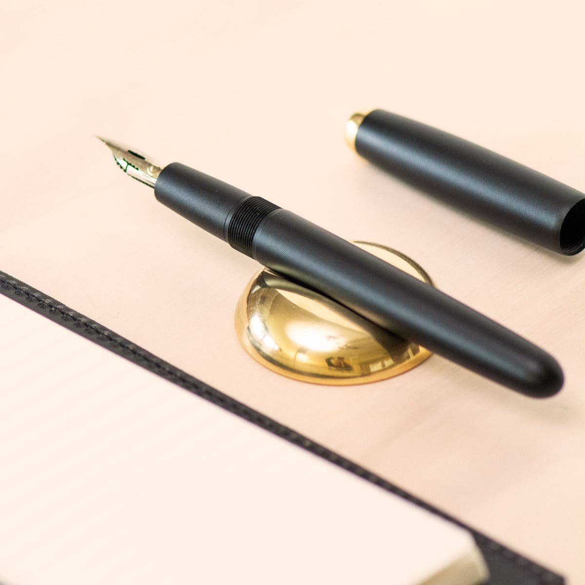 Close-up of black pen on round polished brass pen rest base