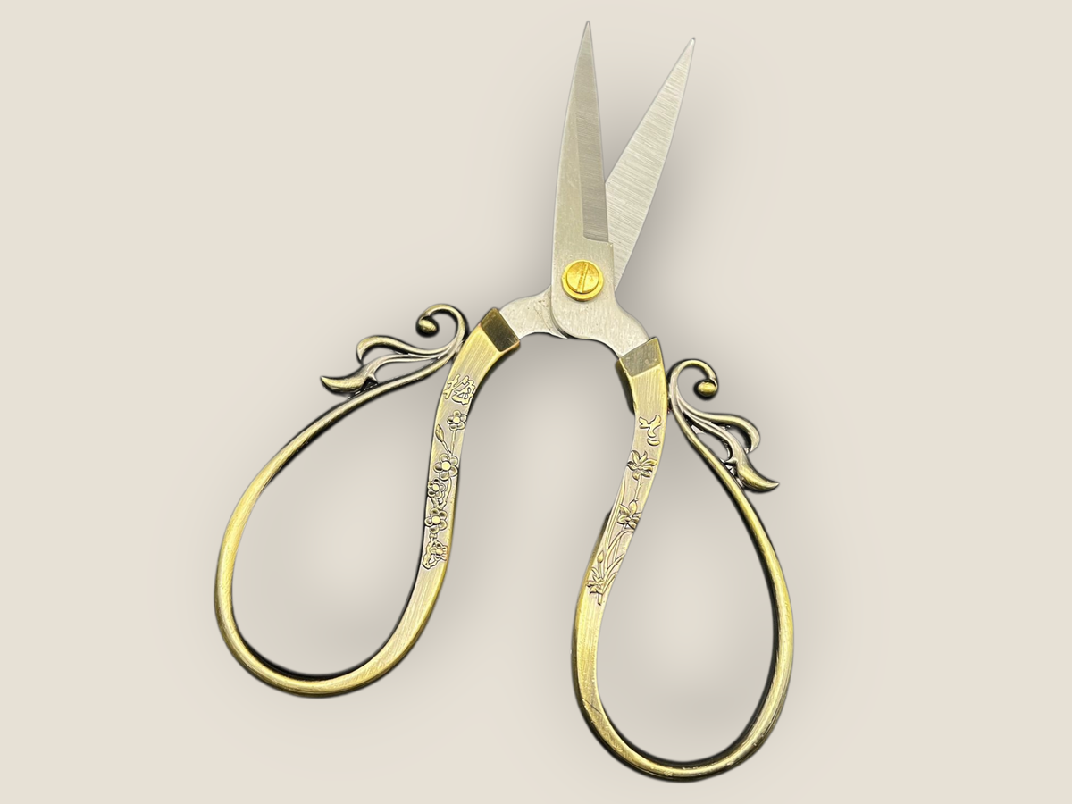 Large cutting scissors with gold-tone filigree loops on handles and long pointed blades
