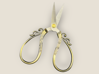Large cutting scissors with gold-tone filigree loops on handles and long pointed blades