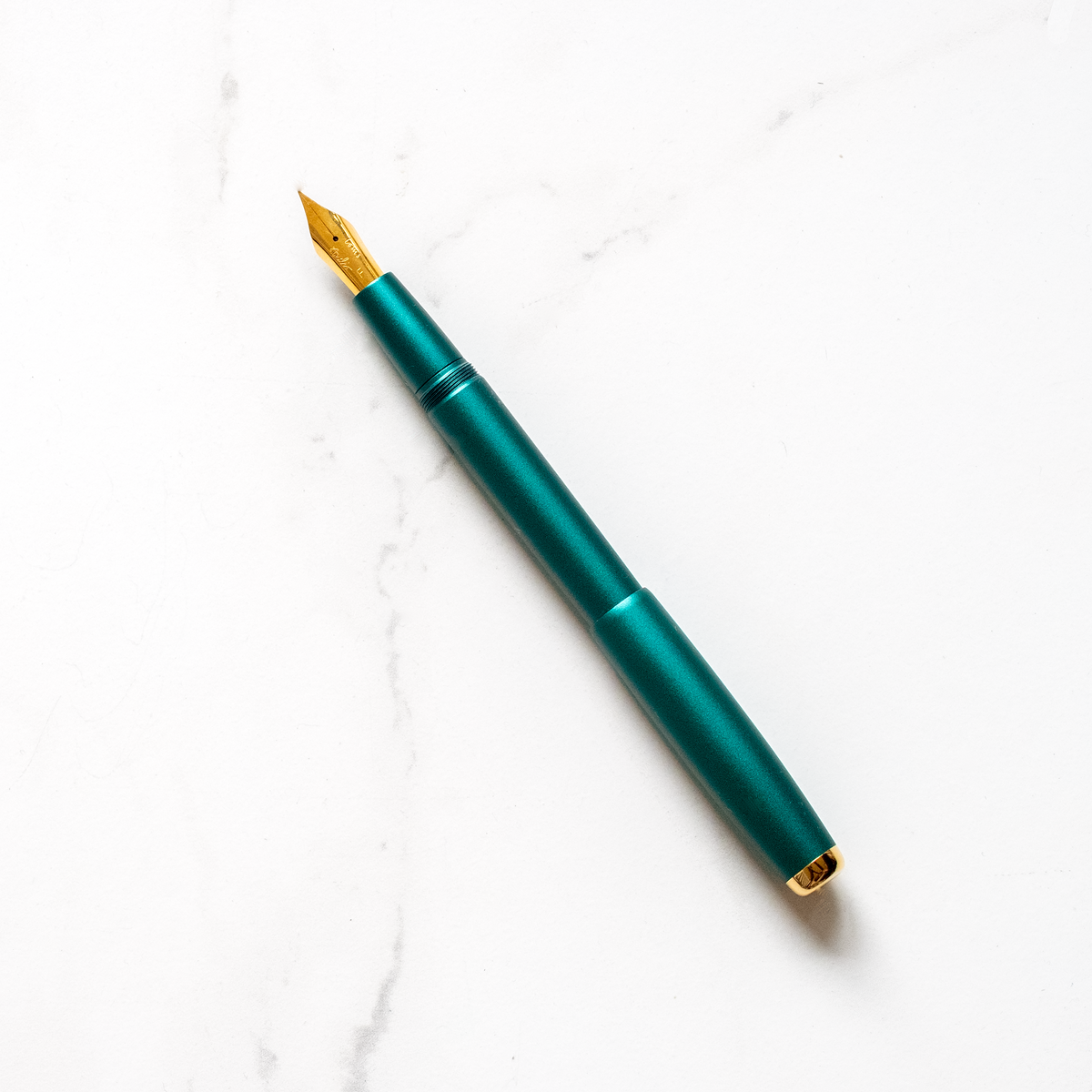 Green fountain pen with gold nib and clip, shown uncapped.
