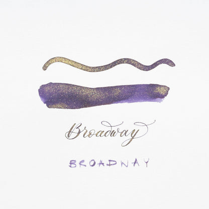 Purple shimmer ink swatch with gold wavy stroke and handwritten label, on white card