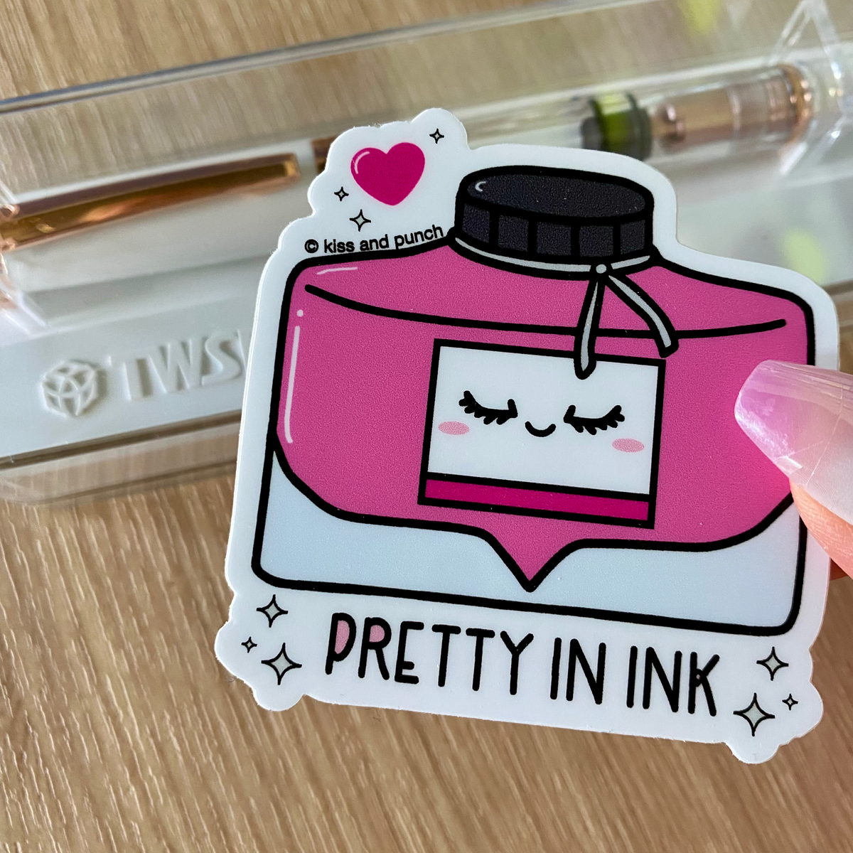 Pink ink bottle fountain pen sticker with cap, wink face, heart, and 'PRETTY INK' text