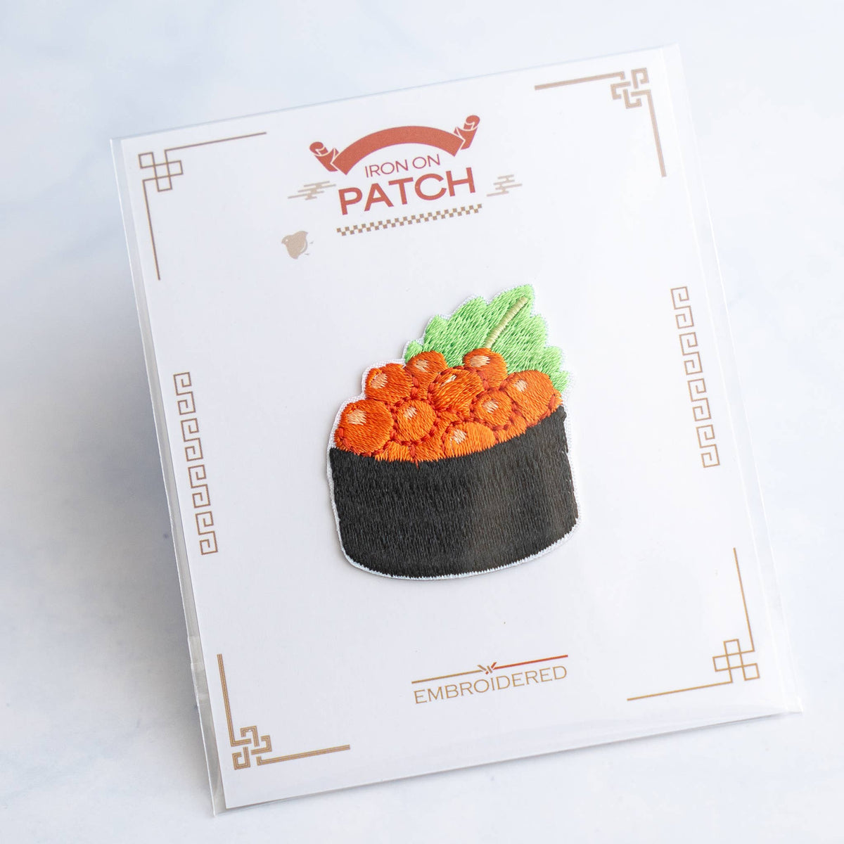 Sushi roe in dark bowl embroidered iron-on patch on card with green garnish