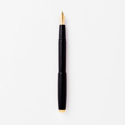 Black fountain pen with gold nib, shown uncapped.