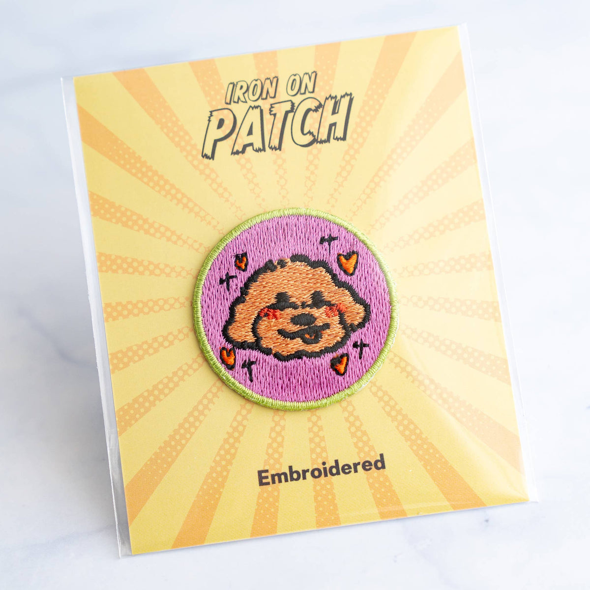 Round embroidered dog iron-on patch with orange-and-black cartoon face on pink