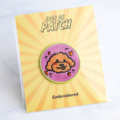 Round embroidered dog iron-on patch with orange-and-black cartoon face on pink