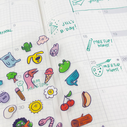 Cartoon stickers from the clear sheet placed on lined planner pages, including “MEETUP NIGHT”