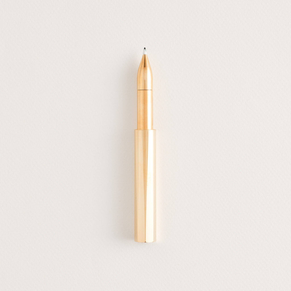 Brass refillable writing pen with exposed copper nib and pointed tip.