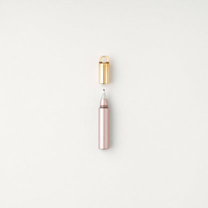 Blush refillable travel pen with open gold cap and pink-tinted tip