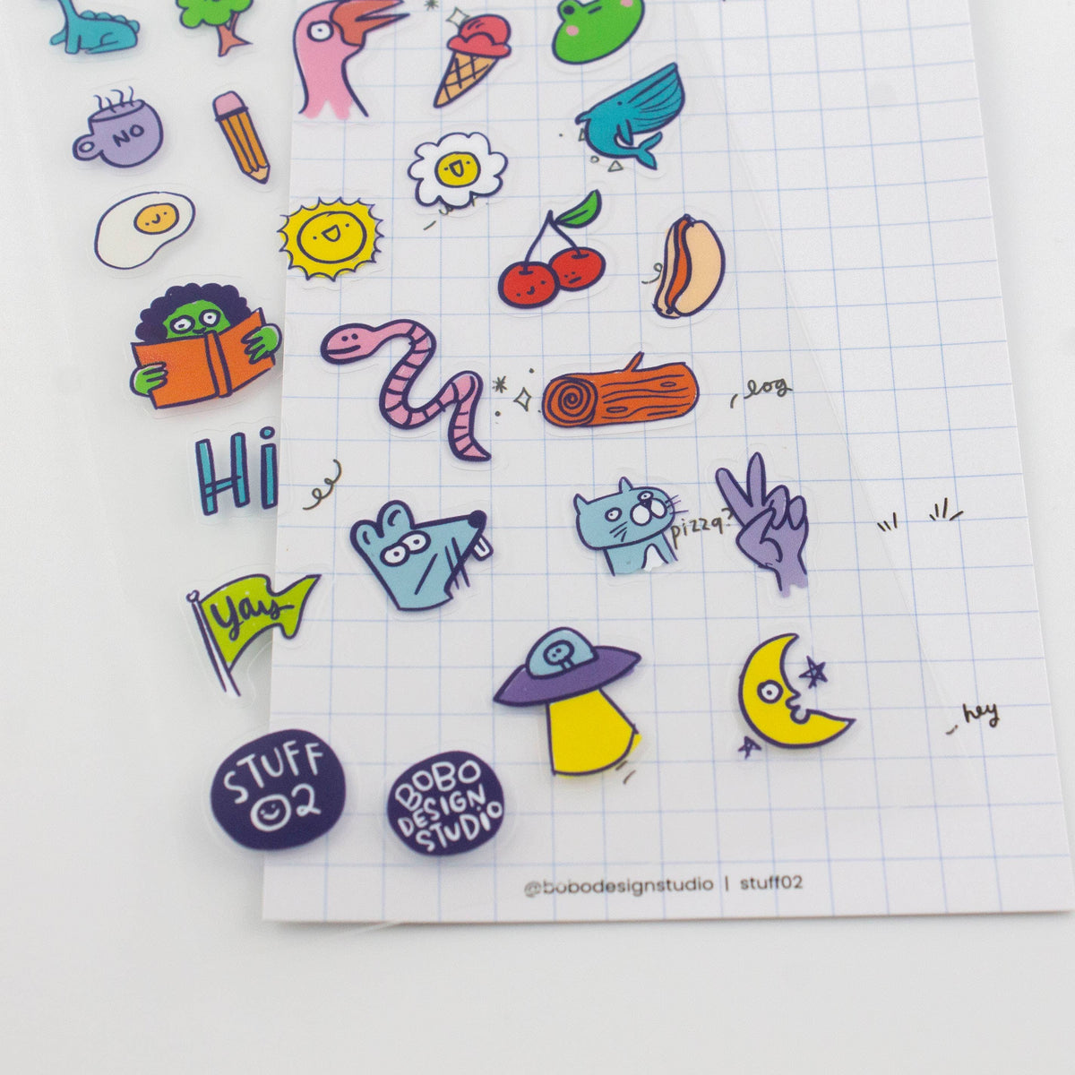 Close-up of clear sticker sheet with colorful icons, including worm, bird, cactus, and cherries