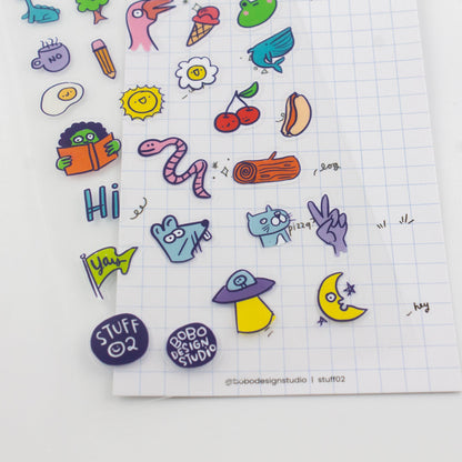 Close-up of clear sticker sheet with colorful icons, including worm, bird, cactus, and cherries
