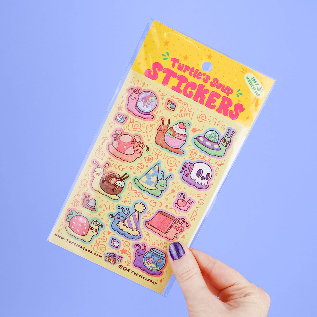 Hand holding glitter sticker sheet with colorful spooky creature stickers
