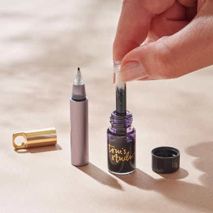 Refillable travel pen with gray barrel, gold cap, and inkwell refill beside it