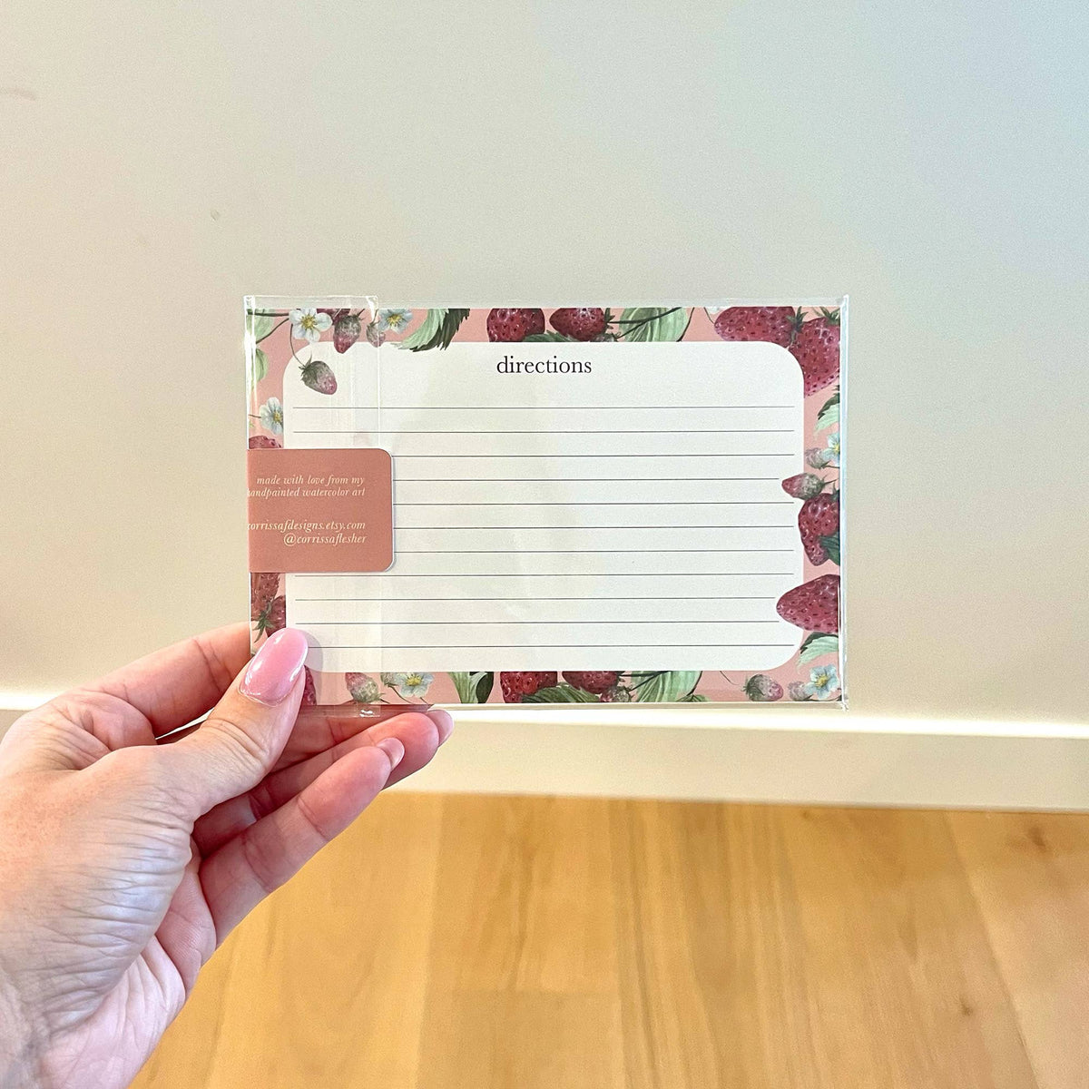 Watercolor strawberry recipe card with directions lines and label, held in hand