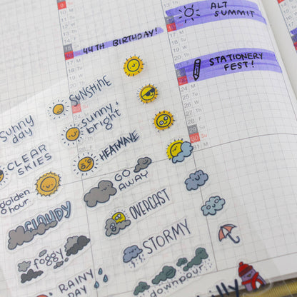 Weather stickers on a planner page, showing sunshine, clear skies, overcast, and rainy