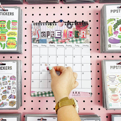 September wall calendar page with spiral binding, shown with a hand pointing at the dates.