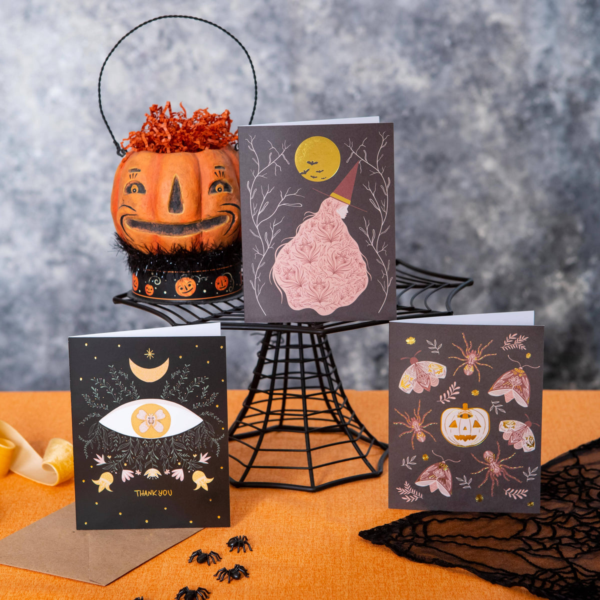 Witch greeting card with a gold moon and pink floral dress among Halloween cards