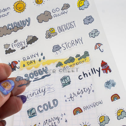 Hand holding weather sticker sheet with soggy, downpour, chilly, cold, and frosty icons