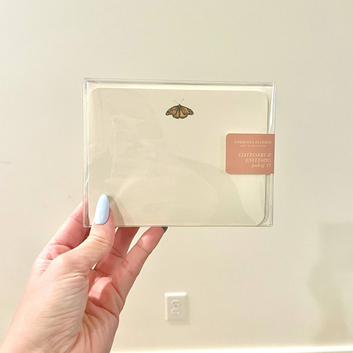 Packaged stationery envelope set in clear sleeve with butterfly motif on cream paper.