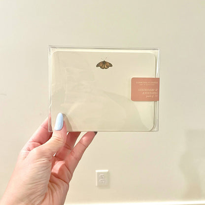 Packaged stationery envelope set in clear sleeve with butterfly motif on cream paper.