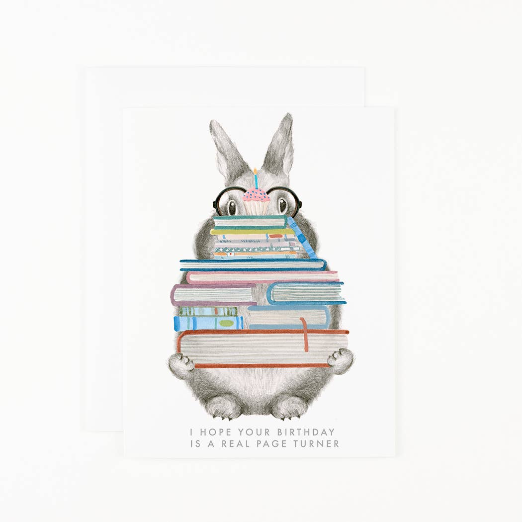 Birthday card with grey rabbit holding stacked books and pink candle; message at bottom