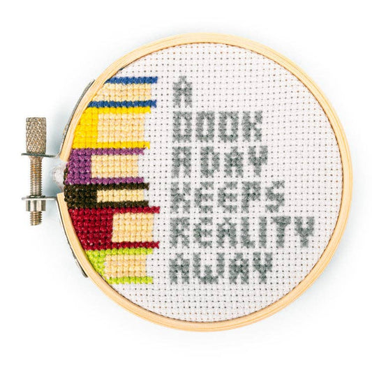 Round embroidery hoop with colorful mini cross-stitch design on white fabric