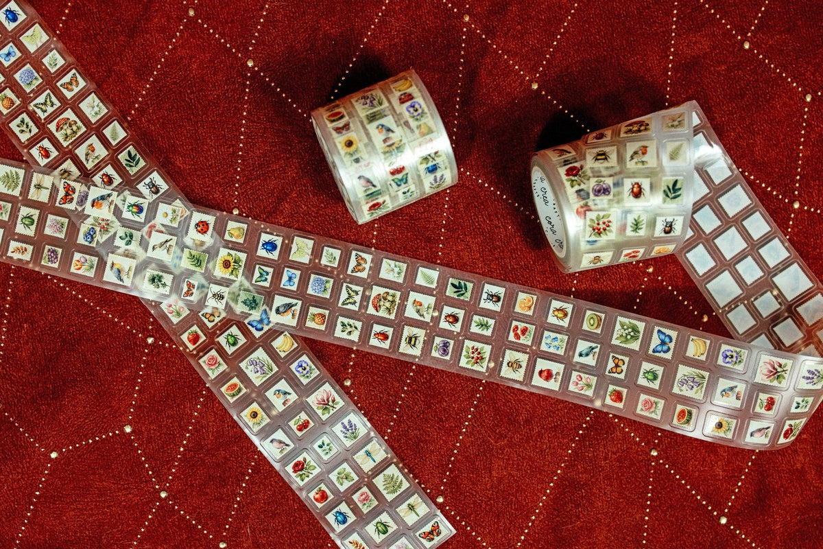 Transparent tape with mini postage stamp designs, two rolls and a long strip laid out