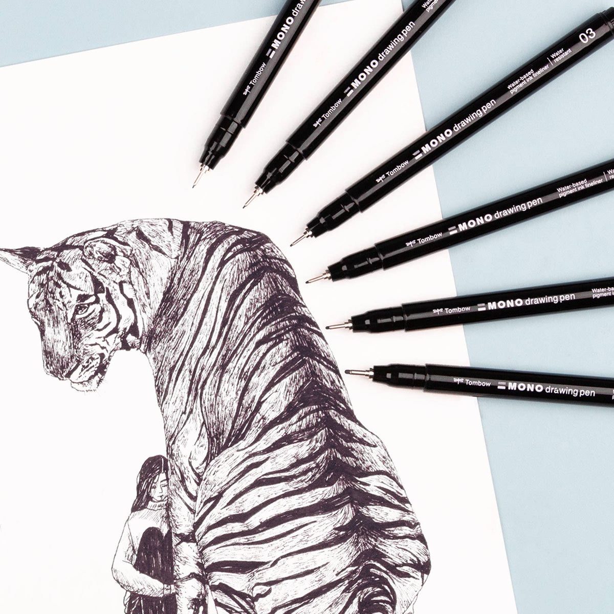 Black fine-tip drawing pens surrounding a detailed animal sketch on paper
