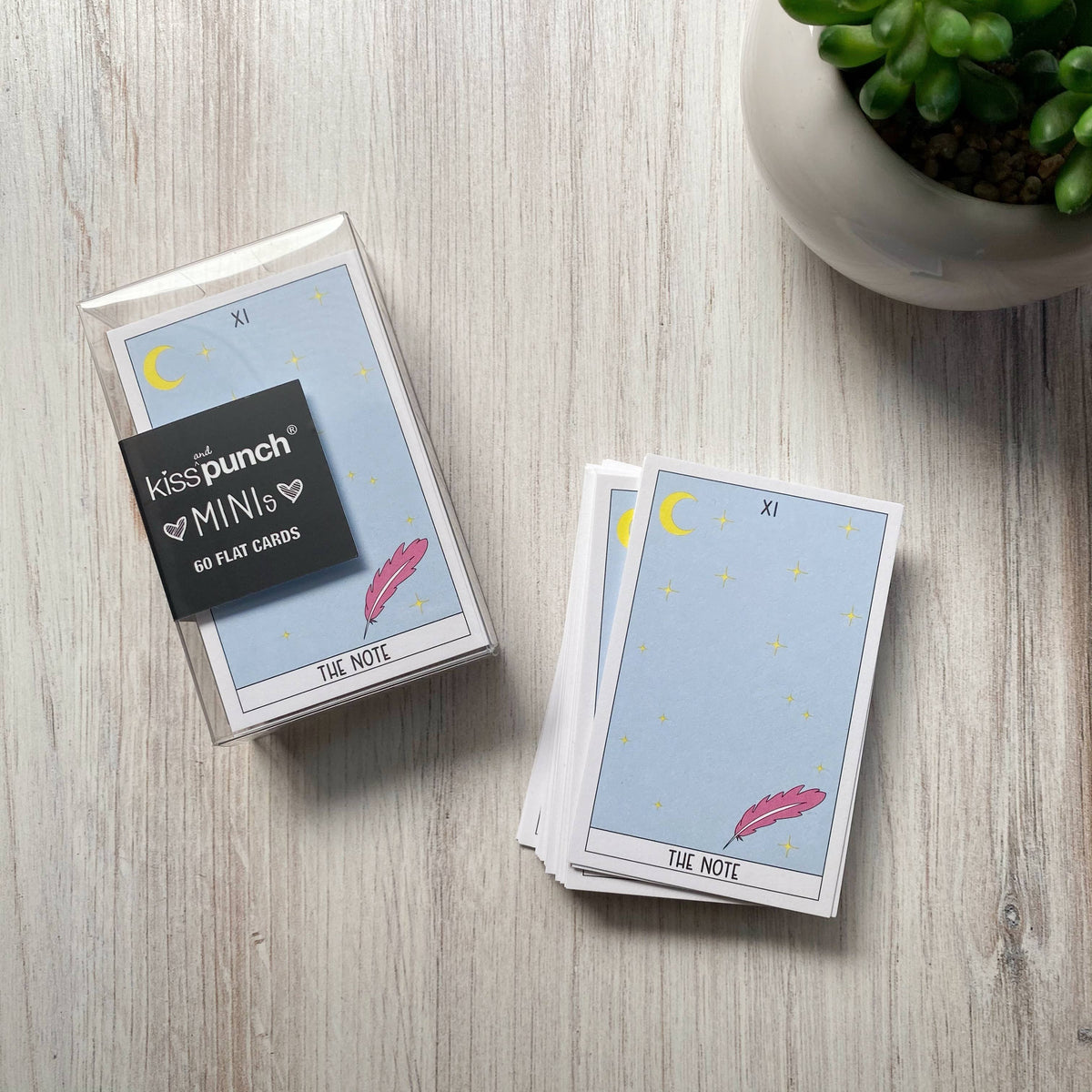 Packaged tarot card mini notecards beside a stack, featuring a moon, stars and feather design.