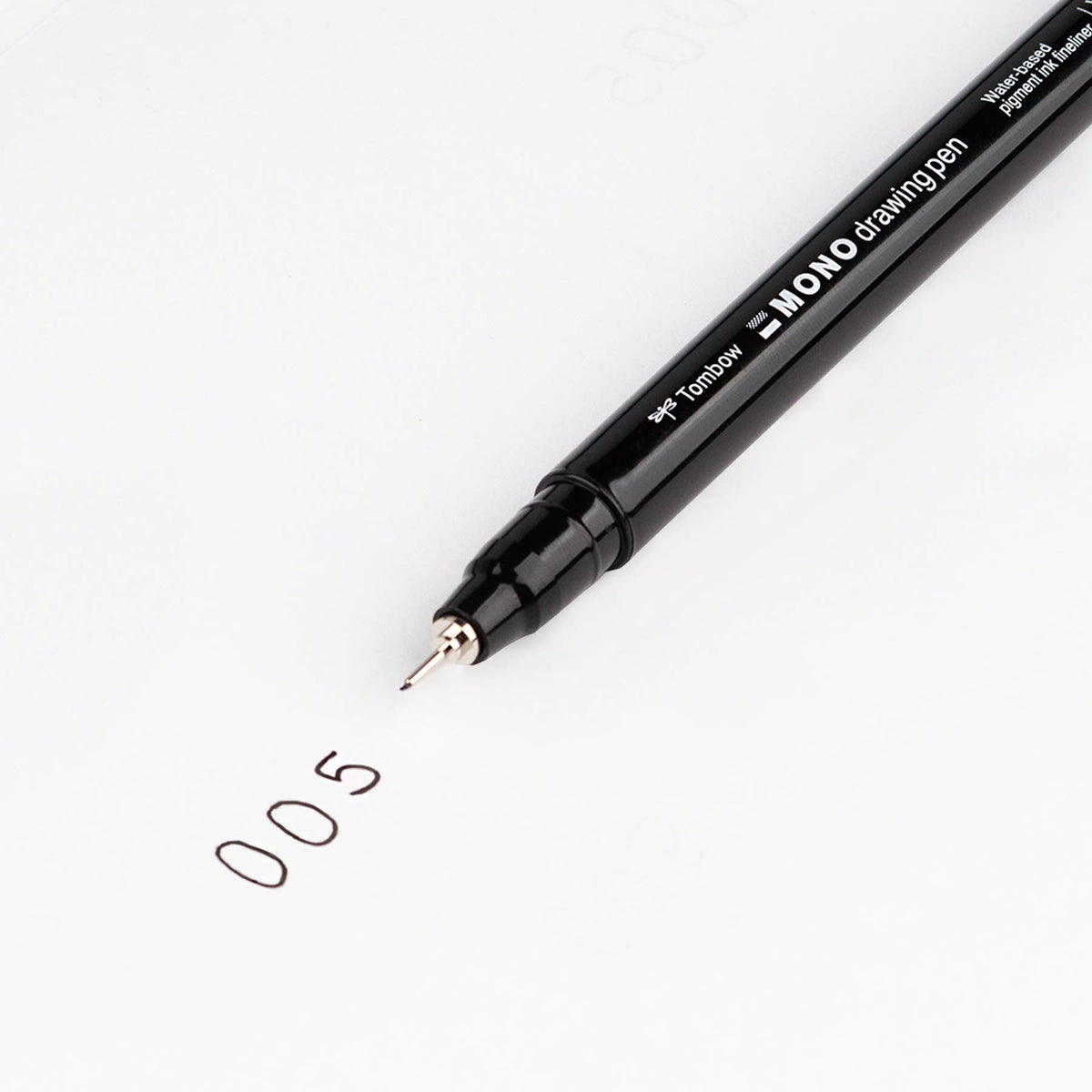 Black fine-tip drawing pen writing a small “0.5” sketch on white paper