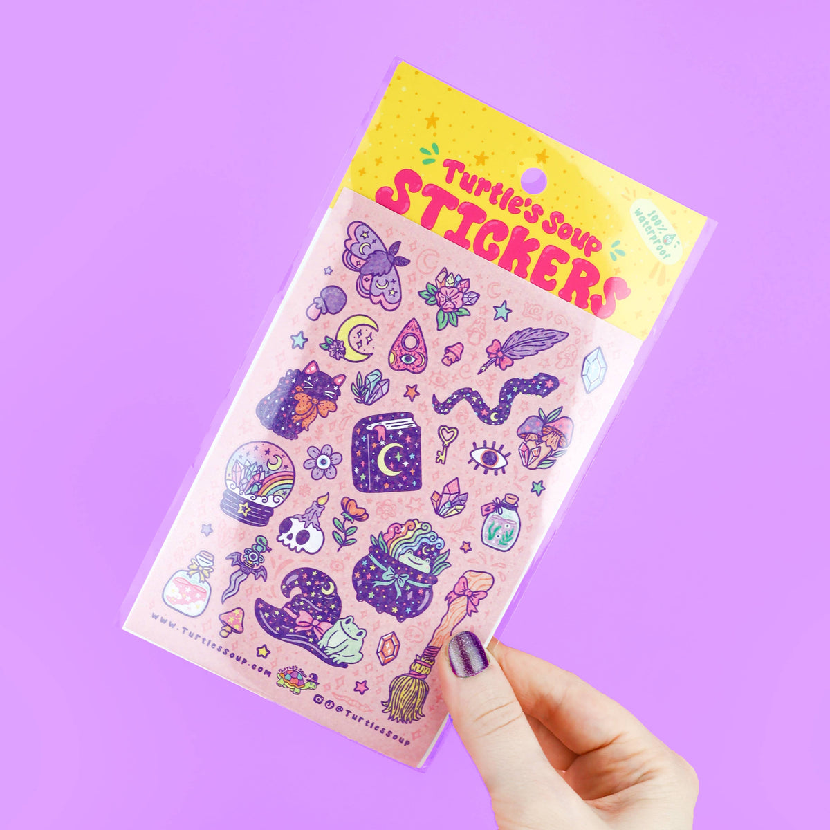 Pastel witch sticker sheet tilted in hand, featuring moon, star, crystal, potion icons