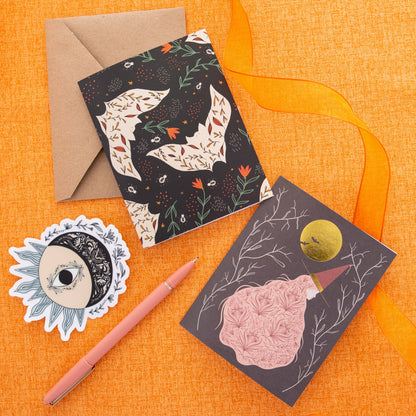 Witch greeting card with a gold moon and pink floral dress beside other Halloween cards
