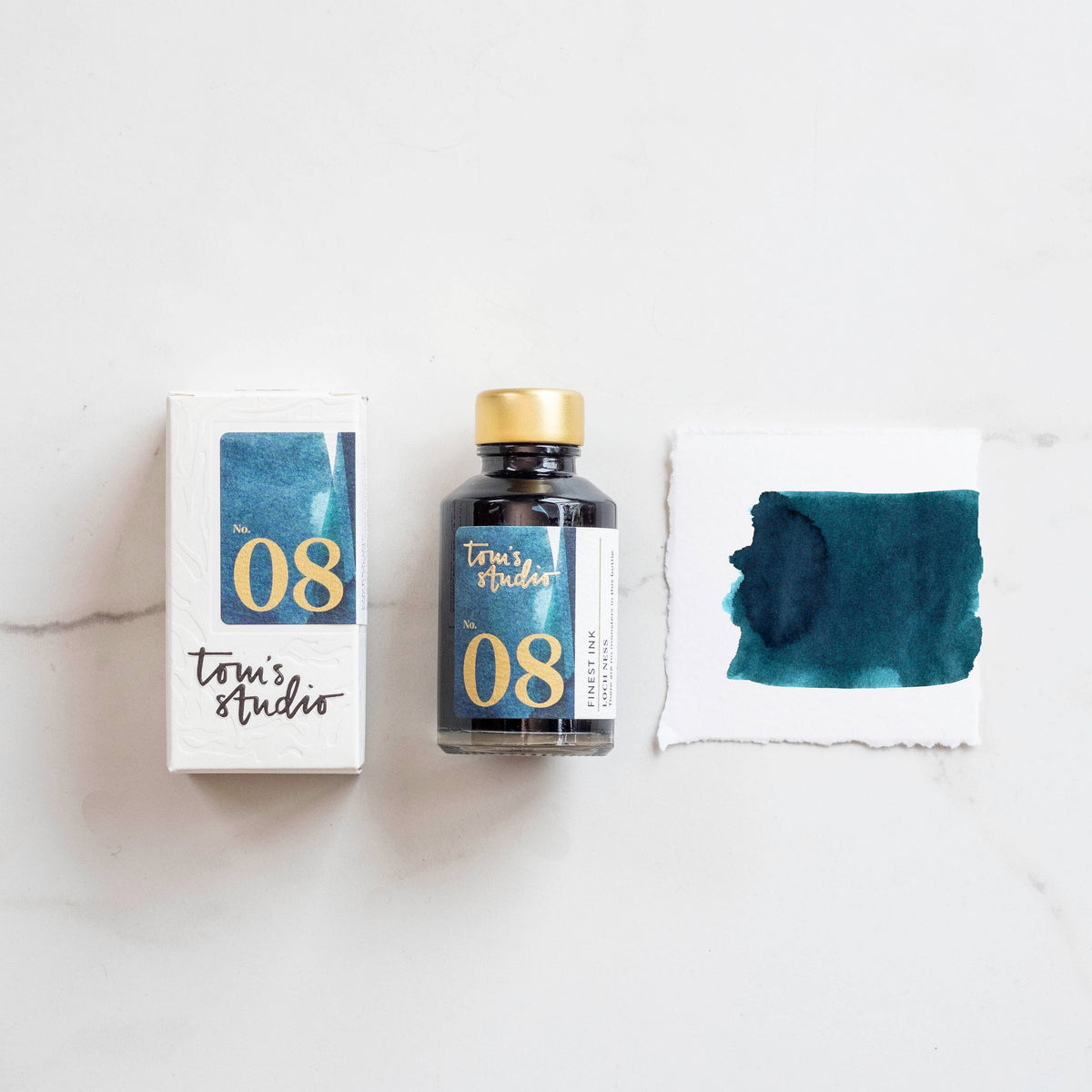 Fountain pen ink bottle with blue-green ink and sample blotter card