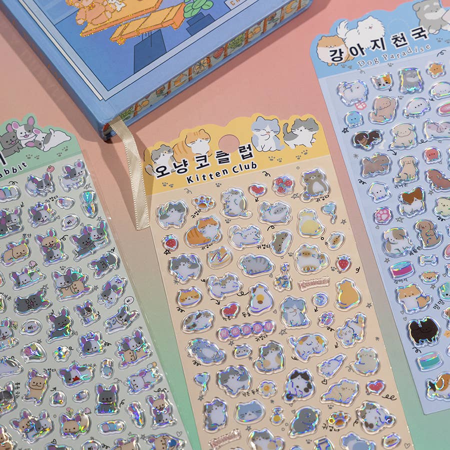 Sticker sheets with cute cat character icons, hearts, and holographic outlines in pastel tones.