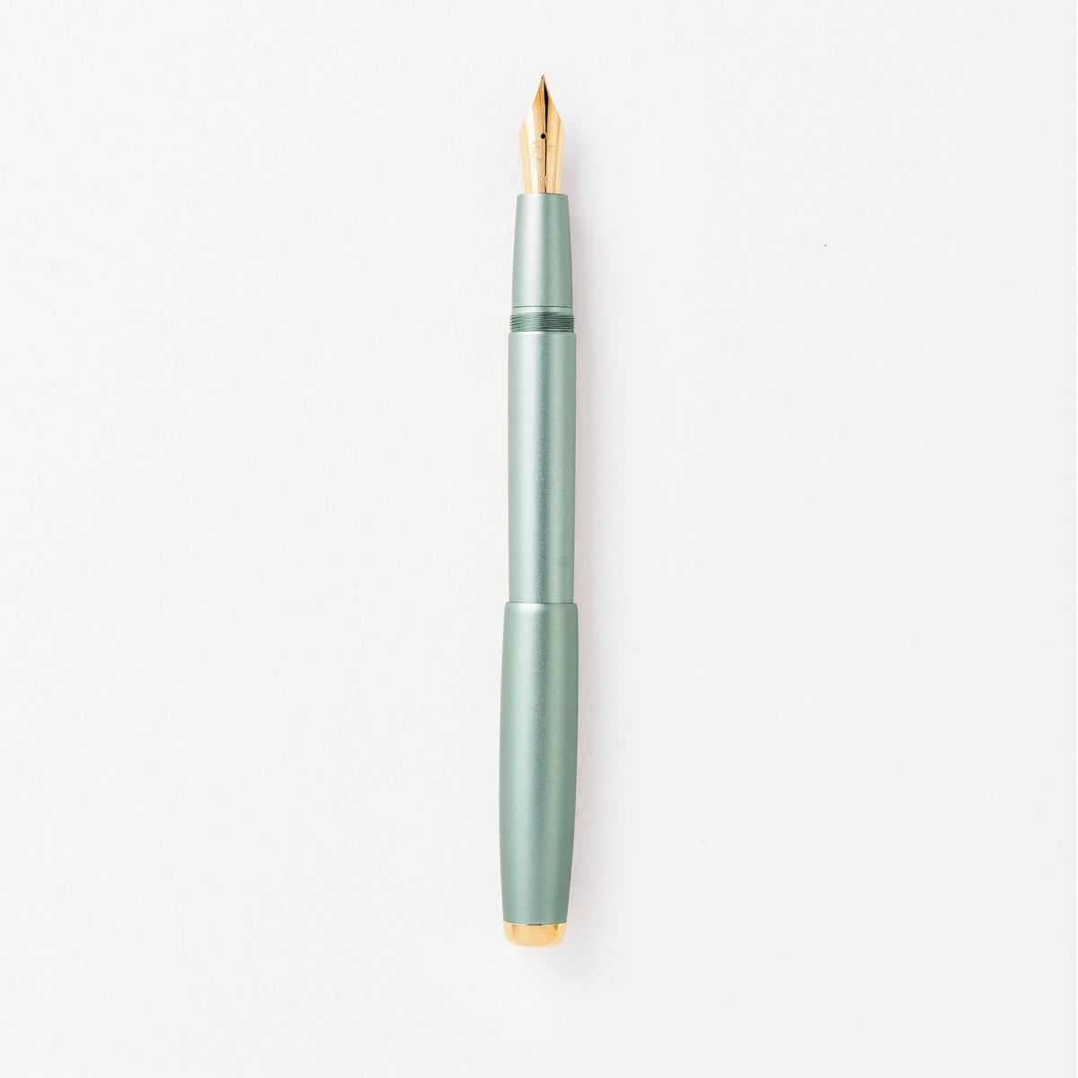 Sage green fountain pen with gold nib, shown upright close-up