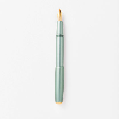 Sage green fountain pen with gold nib, shown upright close-up