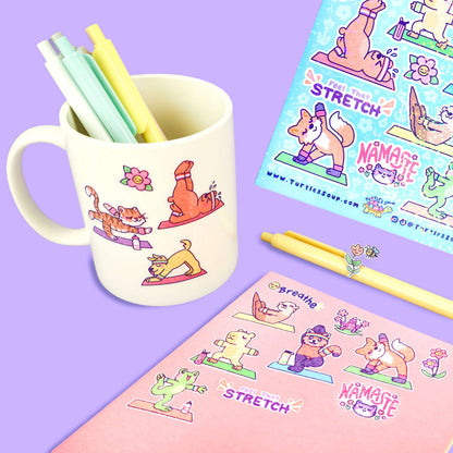 Yoga animal sticker sheet with colorful workout poses, shown beside pen and mug