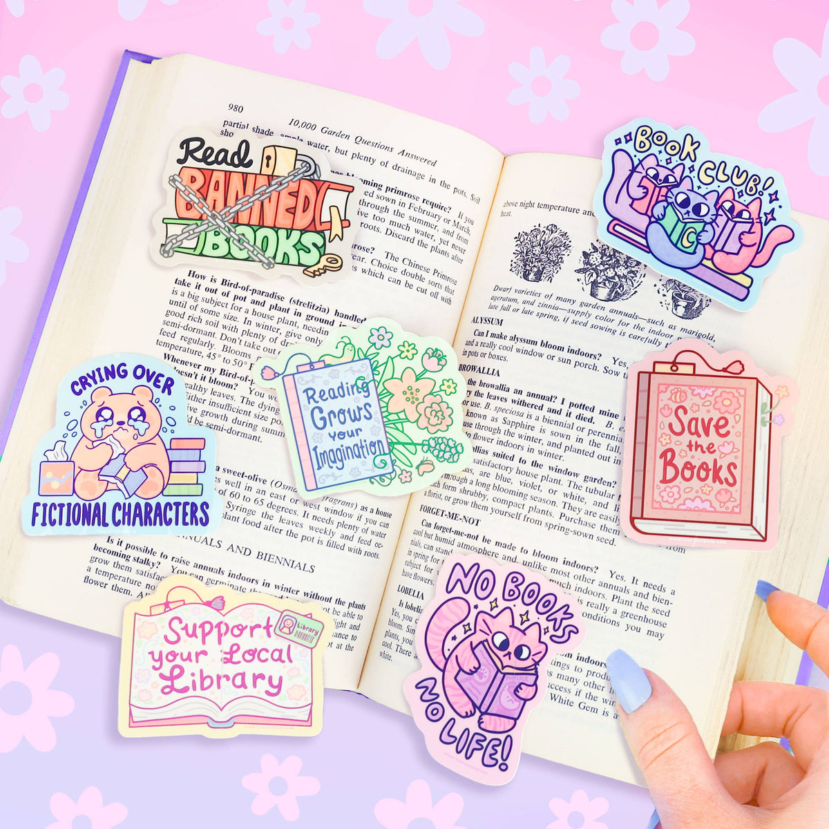 Book club cat vinyl stickers on open reader page, one sticker held in hand