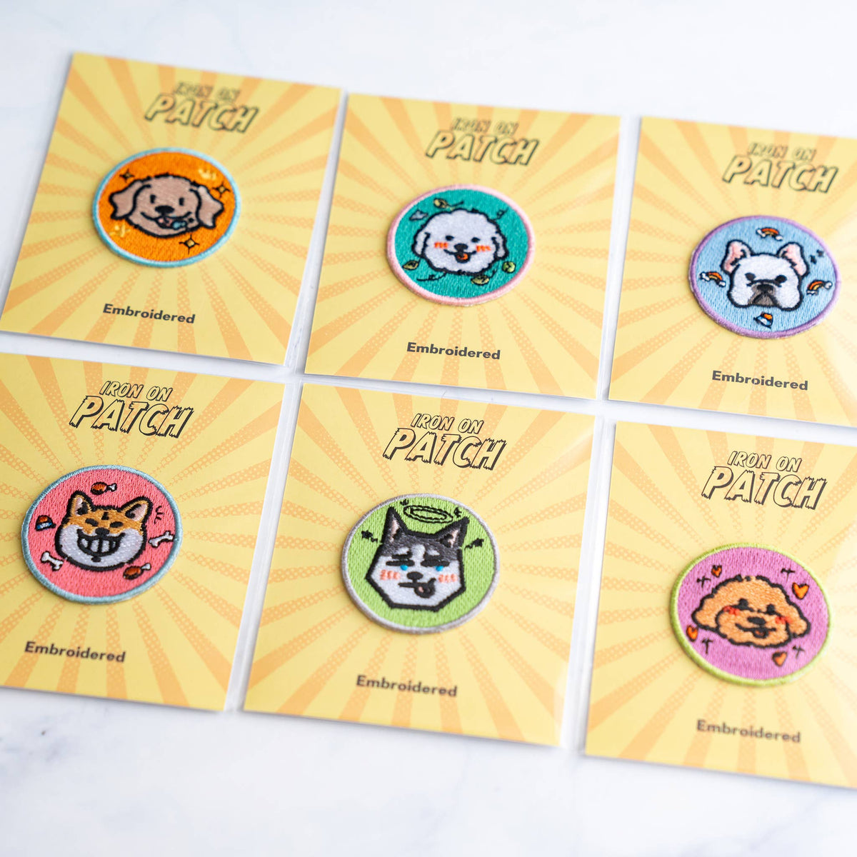 Six-pack of round embroidered dog iron-on patches on yellow cards