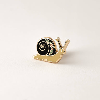 Enamel garden snail lapel pin with black swirl shell, gold-tone body, flower detail