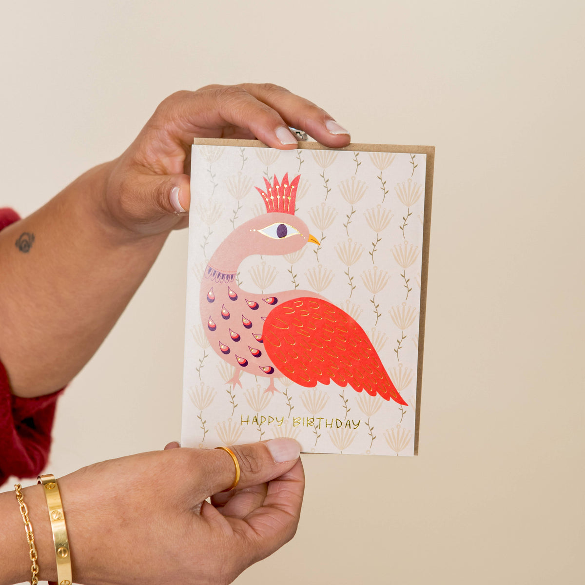 Birthday card featuring a crowned peacock, patterned feathers, and gold foil lettering
