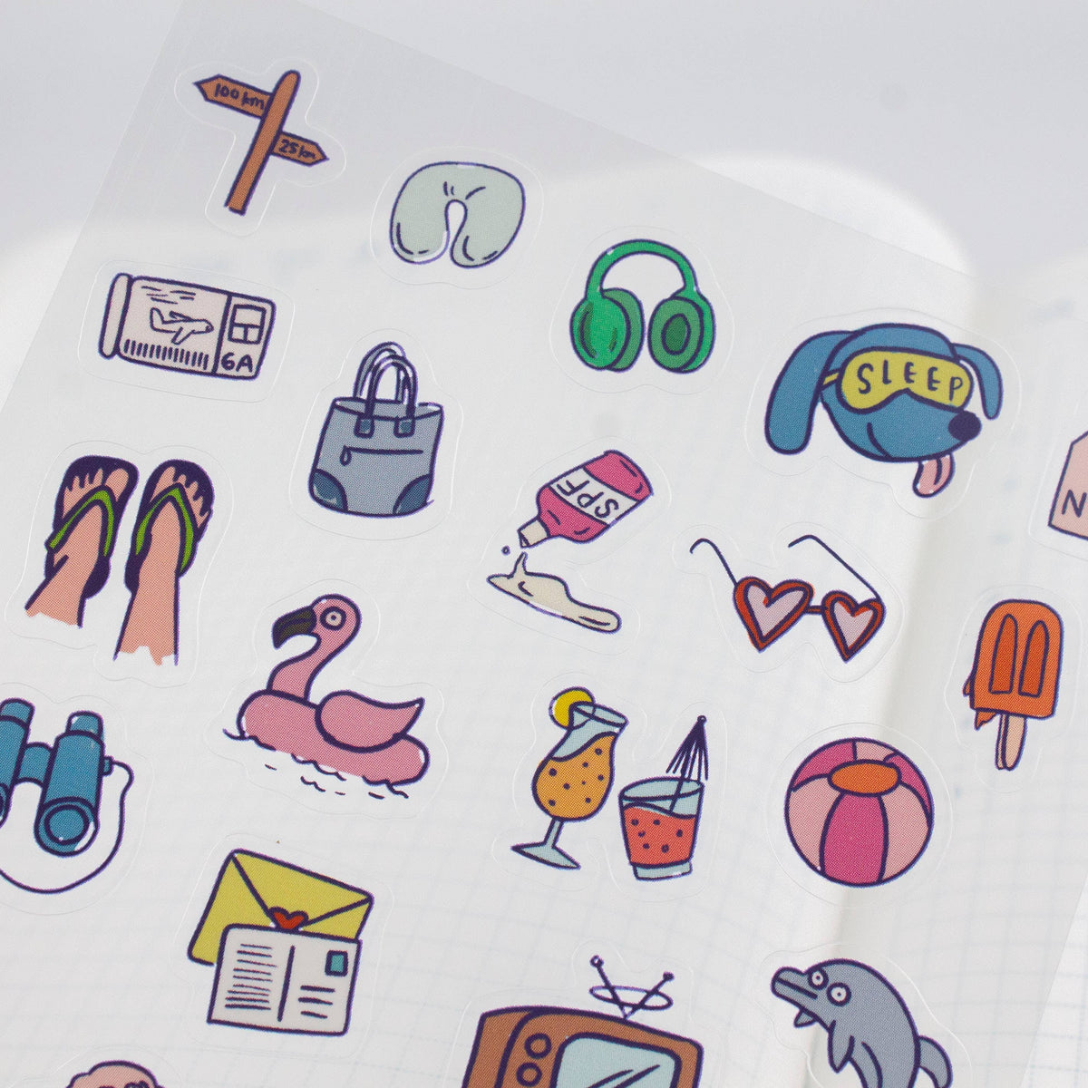 Close-up travel sticker sheet section with headphones, sleep cap, and surf icons